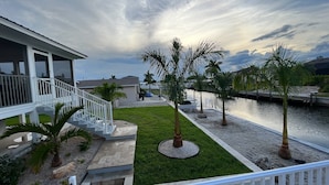 A residential area with a house, a grassy lawn, palm trees, and a canal. - Ga1978 (Englewood)
