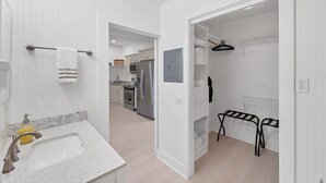 A modern bathroom with a marble sink, a towel rack, and a walk-in closet with shelves and a hanging rack. - Tay307-B (Punta Gorda)