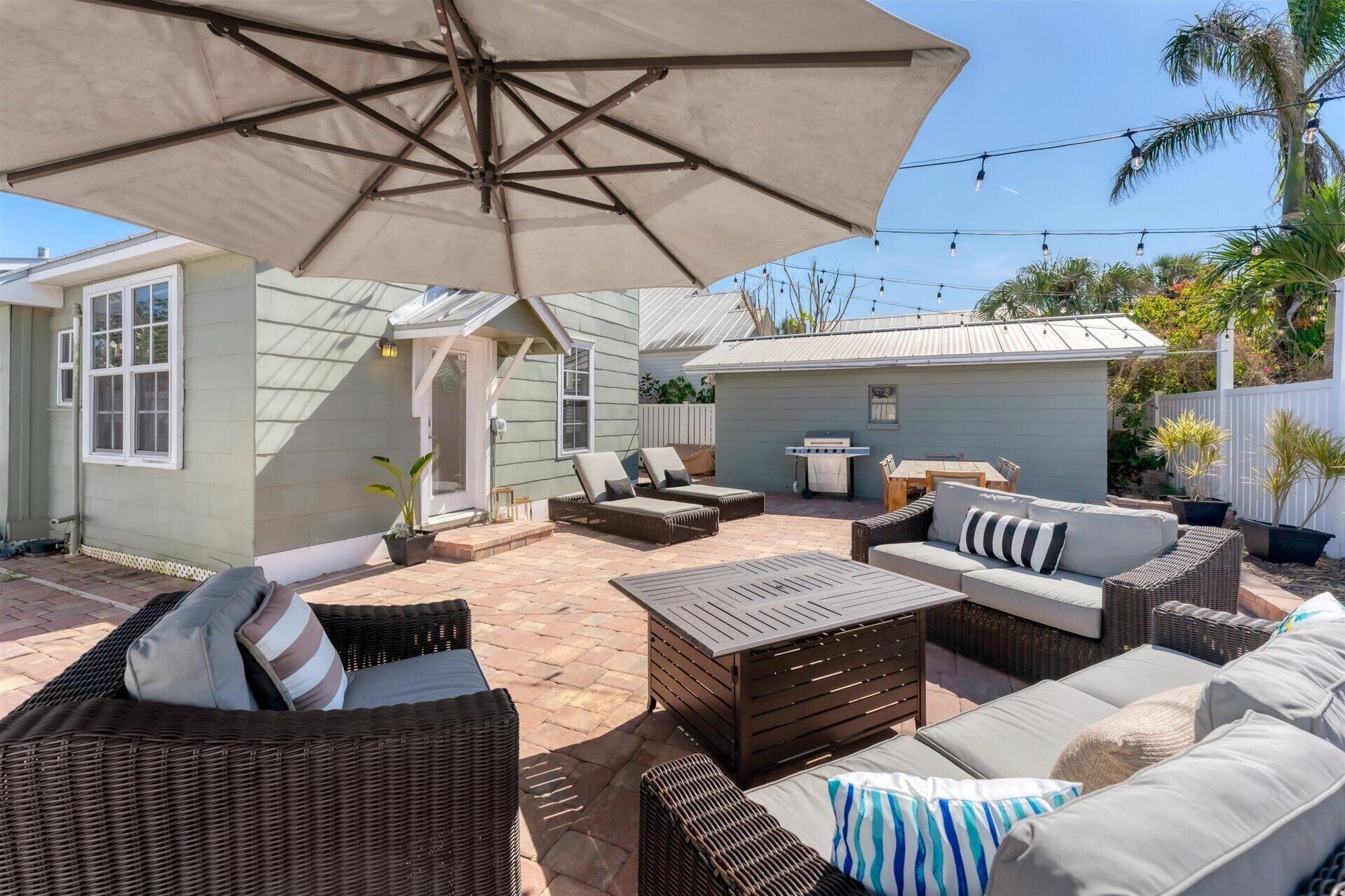 Eine Terrasse mit Korbmöbeln, einem Grill und einem überdachten Sitzbereich.