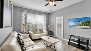 A living room with a sofa, coffee table, TV, and ceiling fan.