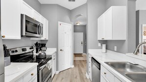 A modern kitchen with white cabinetry, a stainless steel sink, and a microwave.