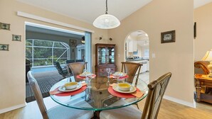 A dining area with a glass table, chairs, and a cabinet.