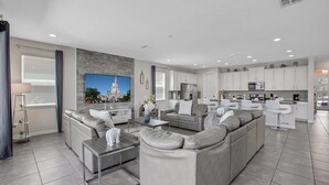 A modern living room with a sectional sofa, a coffee table, and a flat-screen TV mounted on the wall. - Cvt1749 (Kissimmee)