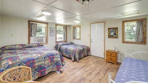 Een slaapkamer met twee bedden, een houten dressoir, een stoel en een plafondventilator.