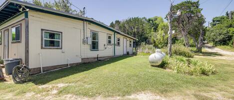 A single-story mobile home with a covered porch, a small front yard, and a large white water tank.