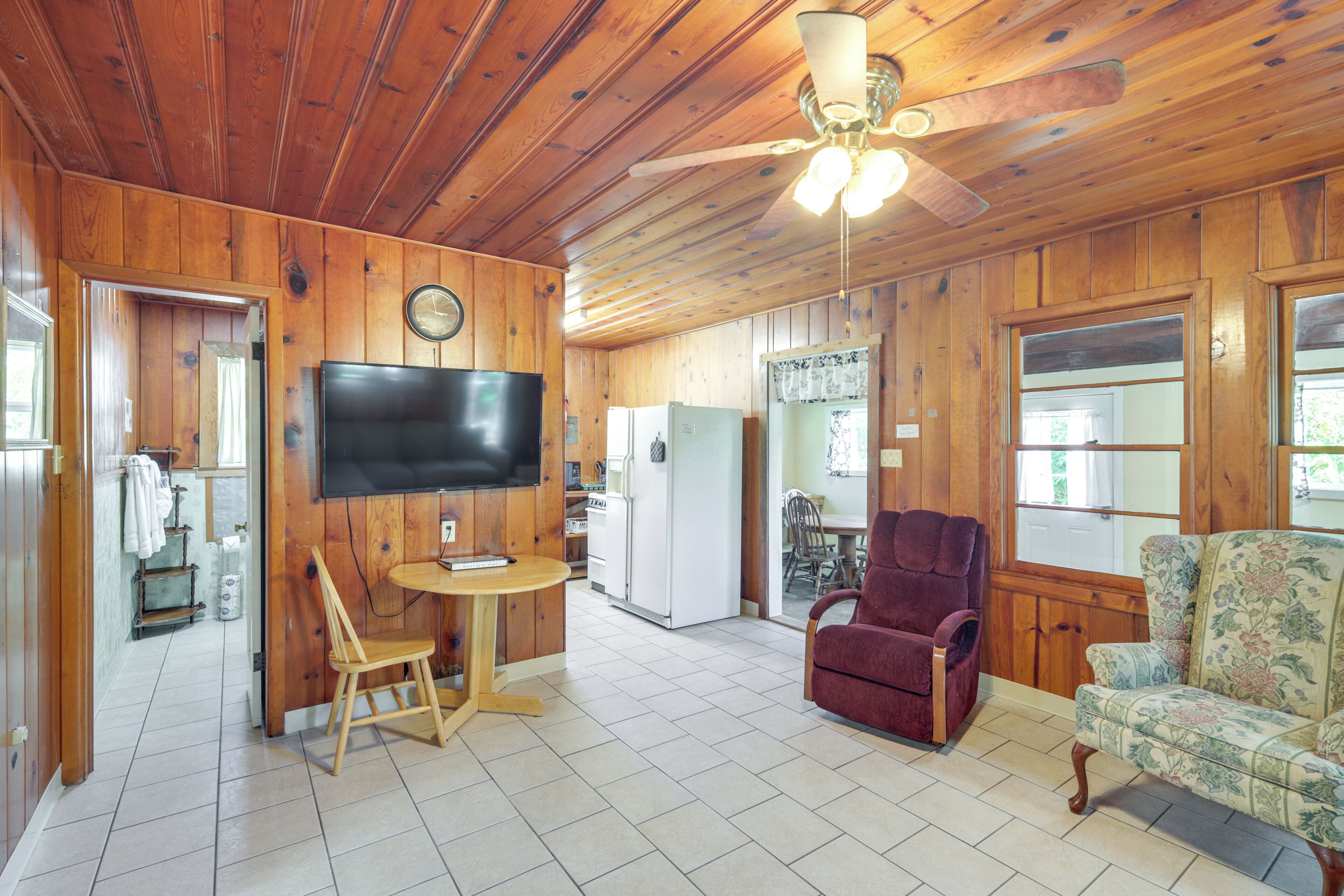 A wooden cabin interior with a dining area, kitchen, and seating.