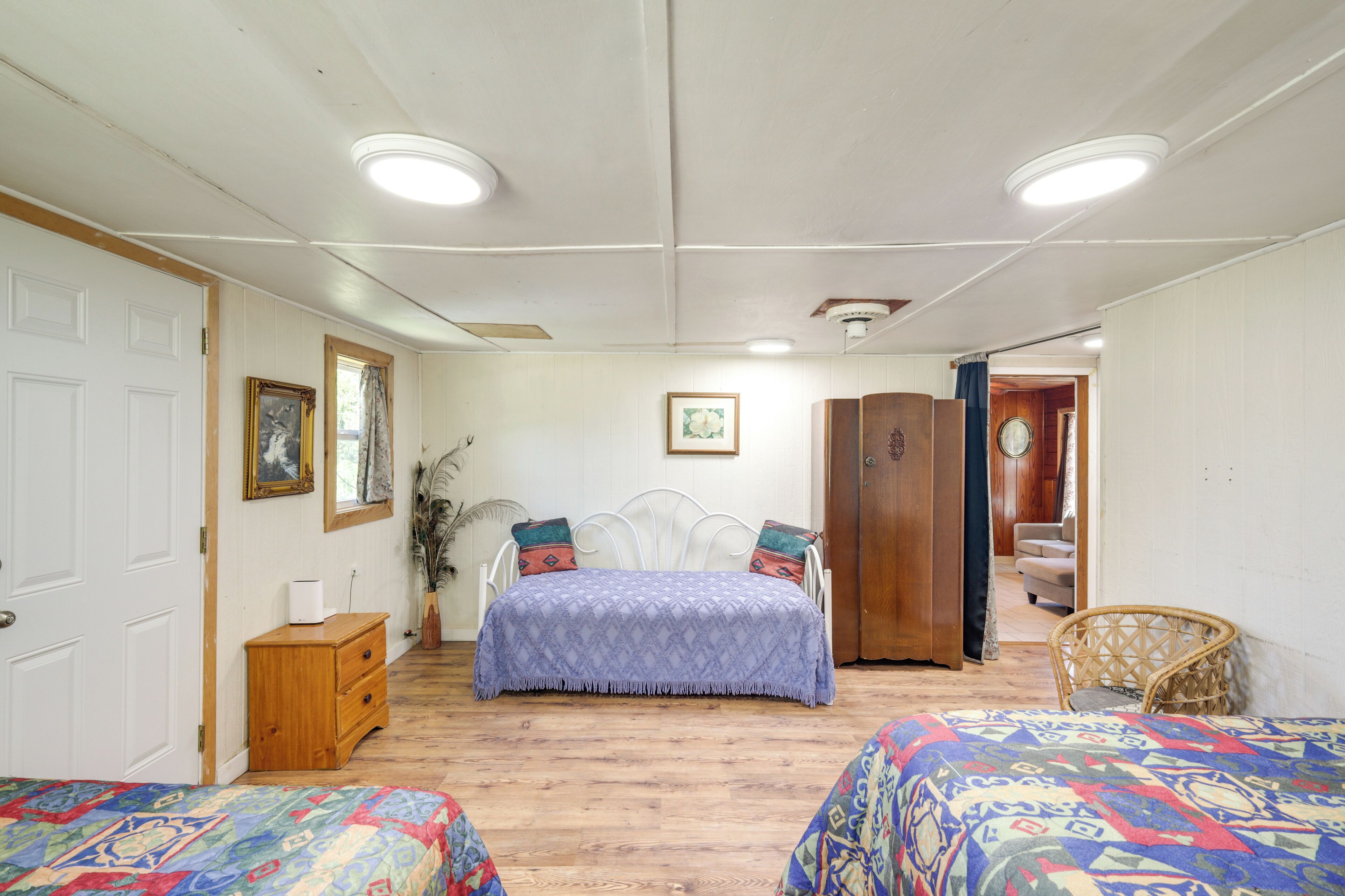 Une chambre avec deux lits, une commode en bois, une chaise et une armoire.