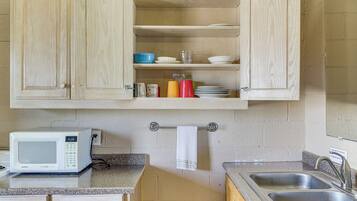 Una cocina con gabinetes de madera, un microondas, un lavabo y un perchero para toallas.