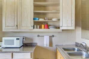 Une cuisine avec des meubles de rangement en bois, un four à micro-ondes, un évier et un porte-serviettes.