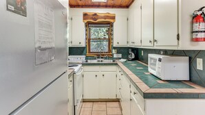 A compact kitchen with white cabinets, a built-in microwave, and a window above the sink.