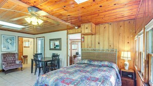 A wooden cabin with a large bed, a dining area, and a ceiling fan.