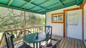 A covered outdoor area with a table and chairs, a door, and a window.