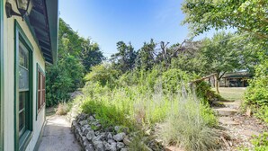 A garden pathway leading to a building with a stone wall and various plants.