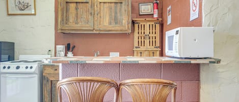 A kitchen with a stove, microwave, and two wicker chairs.