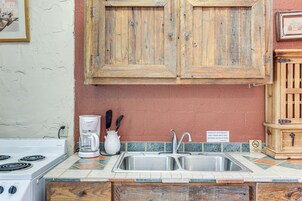 Una cocina con estufa blanca, pileta doble y muebles de madera.