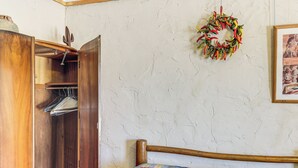 A bedroom with a wooden wardrobe, a bed with a colorful quilt, a wall-mounted wreath, and a framed picture. - Studio w/ Trail Access: 8 Mi to Lake Whitney St Pk (Whitney)