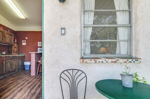 Una cocina con armarios de madera, un cubo de basura y una ventana con cortinas.