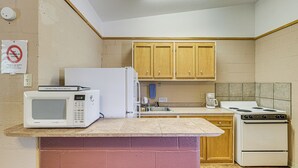 Cocina compacta con electrodomésticos básicos, incluyendo microondas, refrigerador, lavaplatos y estufa.