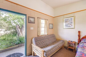 Una habitación con sofá, una pequeña mesa de madera, cama y ventana con cortinas.