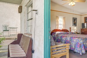 A bedroom with a bed, a wooden bench, a chair, a nightstand, and a television. - Hike On-site: Lake Whitney Studio Hideaway (Whitney)