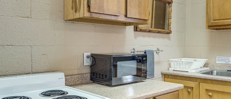 A kitchen with a stove, microwave, and wooden cabinets.