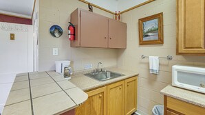 A compact kitchen with a sink, wooden cabinets, a microwave, and a fire extinguisher. - Easy Lake & Hiking Trails Access: Whitney Studio (Whitney)