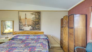 Quarto com cama, cabeceira de madeira, pintura de uma paisagem nevada, guarda-roupa de madeira e uma cadeira.