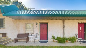 A building with a red door, a bench, a small table, and a chair outside. - Easy Lake & Hiking Trails Access: Whitney Studio (Whitney)