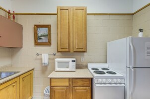 Cocina con armarios de madera, un microondas, estufa y refrigerador.