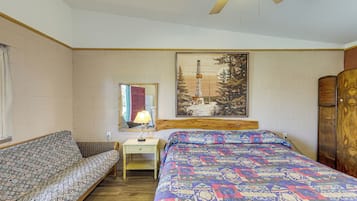 Un dormitorio con cama, sofá, mesita de noche, espejo y un cuadro en la pared.