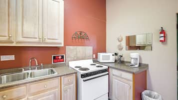 A kitchen with a stove, microwave, sink, and cabinets.