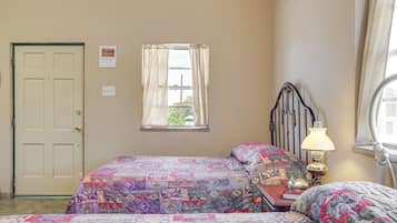 Un dormitorio con dos camas, una ventana con cortinas, una lámpara de noche y una puerta.