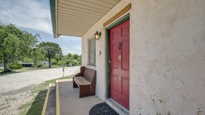 A building with a red door, a bench outside, and a doormat. - Relax Fireside! Lake Whitney Studio 2 Mi to Marina (Whitney)