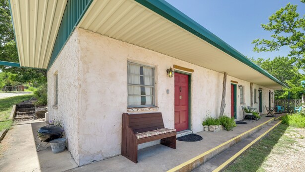 A single-story building with a red door, a bench outside, and a covered porch area. - Relax Fireside! Lake Whitney Studio 2 Mi to Marina (Whitney)