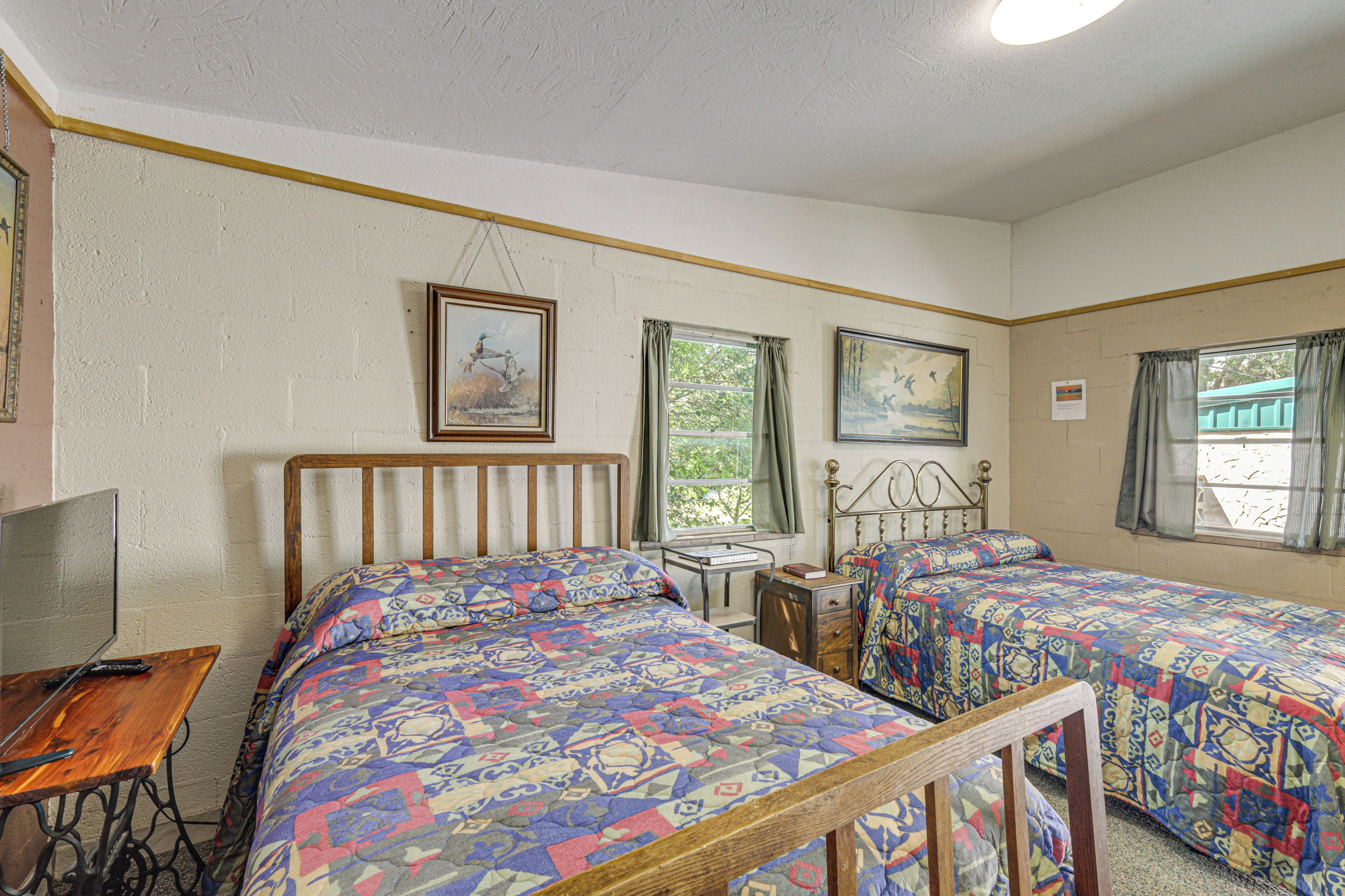 A room with two beds, a desk, and a window.