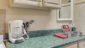 Eine Küche mit Kaffeemaschine, Geschirr, Spüle und einem Rauchverbot-Schild.
