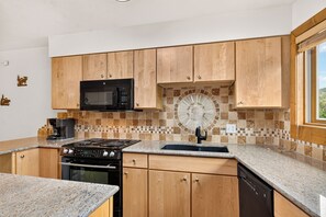 A kitchen with wooden cabinets, a microwave, a stove, and a tiled backsplash. - Top-Floor Ski-In Condo | Walk to Lifts & Main St (Breckenridge)
