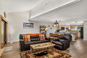 A modern living room with a sofa, armchair, and coffee table, a kitchen in the background, and a dining area. - Top-Floor Ski-In Condo | Walk to Lifts & Main St (Breckenridge)