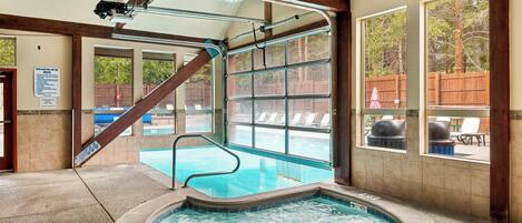 A hot tub area with a view of a pool and outdoor seating.
