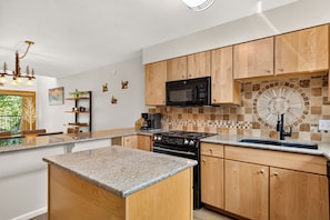 A modern kitchen with wooden cabinets, a built-in microwave, a gas stove, and a tiled backsplash.
