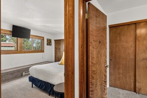 Ein Schlafzimmer mit einem Bett, einem Nachttisch, einem Fenster und einer Tür.