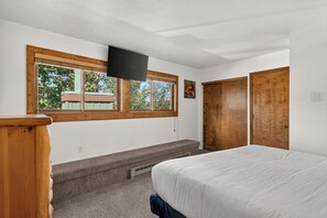 Un dormitorio con cama, ventana, televisor y armario.