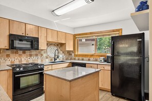 A modern kitchen with wooden cabinets, a black refrigerator, a stove, and a microwave. - Top-Floor Ski-In Condo | Walk to Lifts & Main St (Breckenridge)