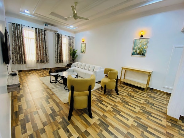 Una sala de estar con un sofá, dos sillones, una mesita de centro y una consola de madera.
