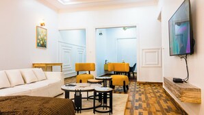 A modern living room with a sofa, yellow chairs, a coffee table, and a TV mounted on the wall.