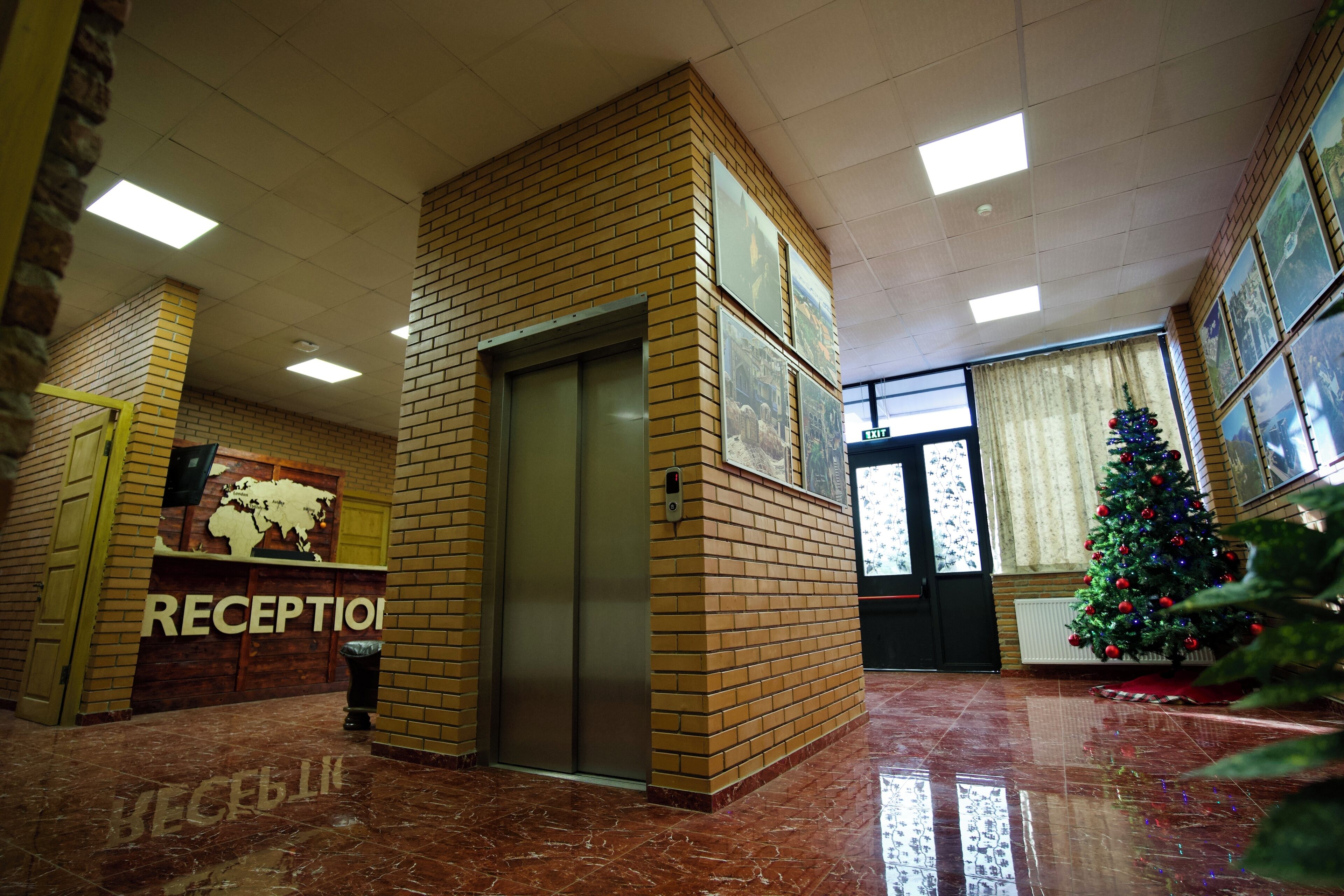 A reception area with a brick wall, a reception desk, an elevator, and a Christmas tree.
