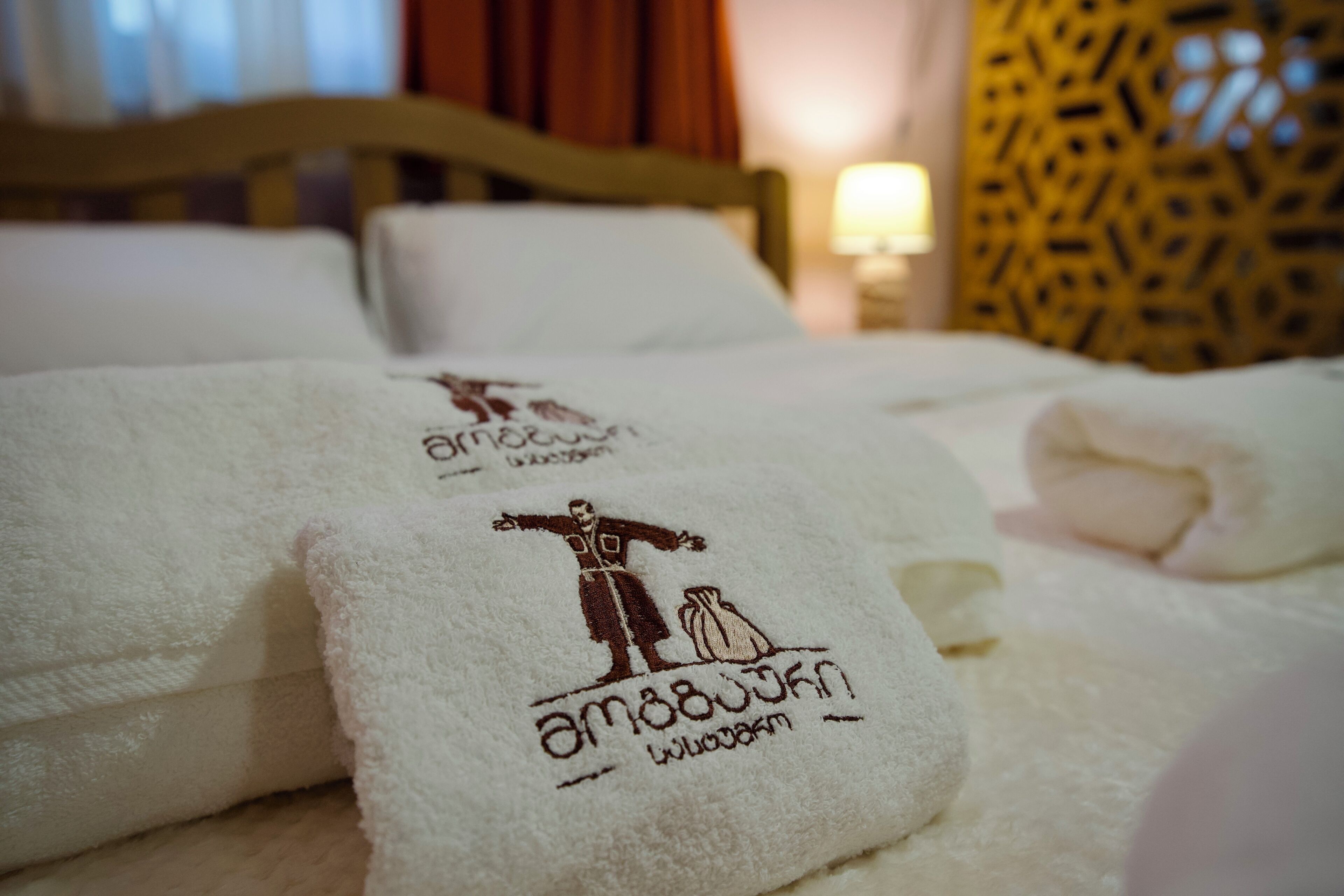Un letto rifatto con asciugamani bianchi con un logo e un testo.