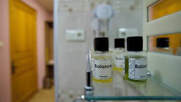 A bathroom with a glass shelf holding two bottles of Balance shampoo and shower gel.
