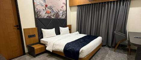 A modern hotel room with a large bed, a desk, and a chair.