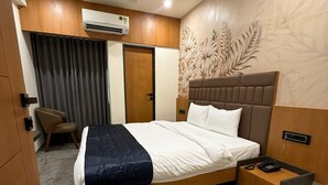 Une chambre d’hôtel moderne avec un grand lit, une table de chevet, une chaise et un ventilateur de plafond.
